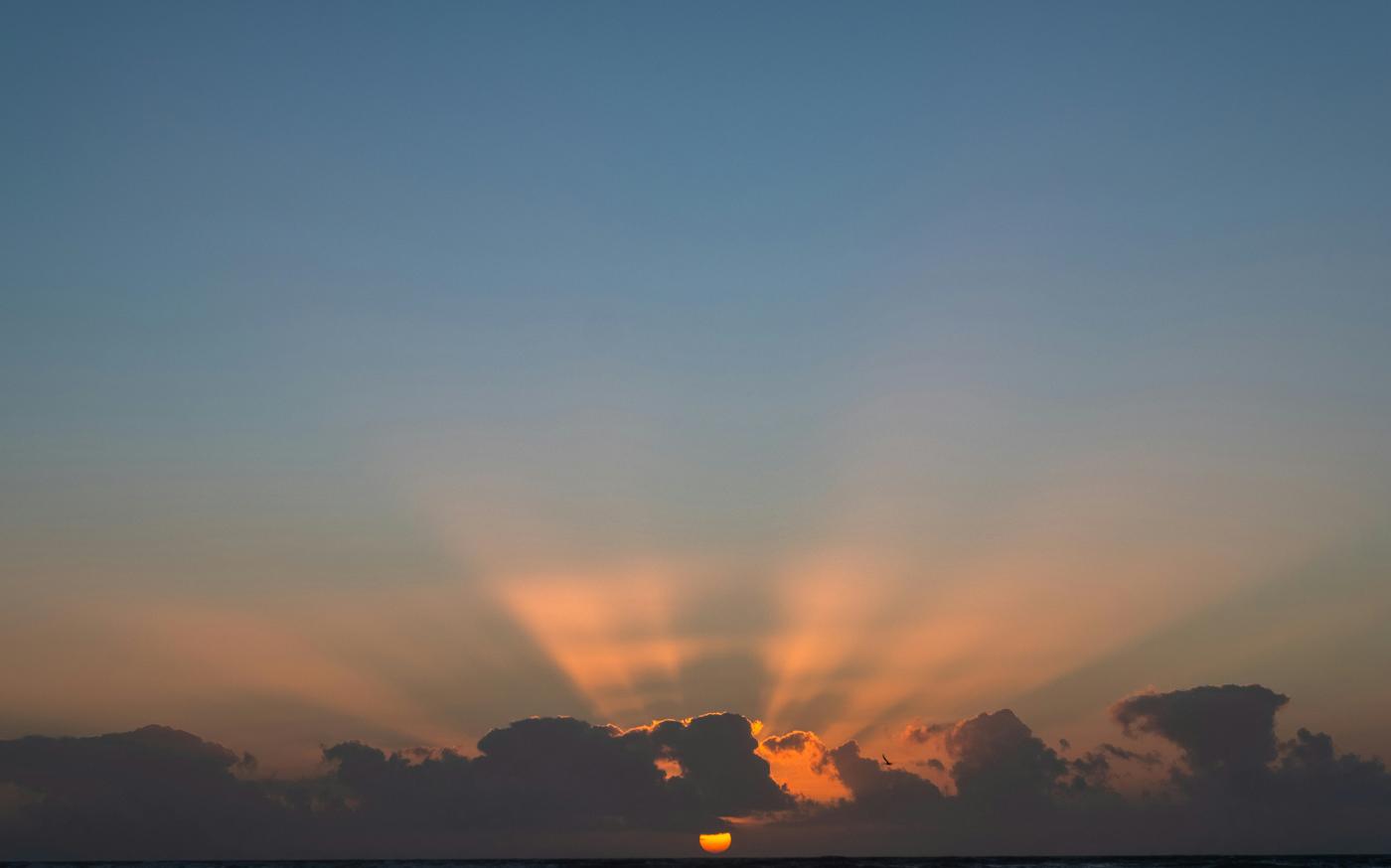 The sun is setting over a body of water by Klanarong Chitmung courtesy of Unsplash.