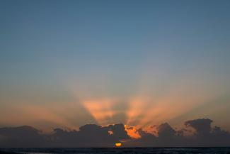 The sun is setting over a body of water by Klanarong Chitmung courtesy of Unsplash.